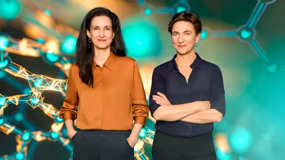 Beke Schulmann und Korinna Hennig stehen vor einem abstrakten, wissenschaftlich anmutenden Hintergrund mit leuchtenden Molekülstrukturen. Beide blicken freundlich in die Kamera.