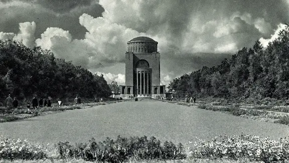 Blick auf den Wasserturm im Hamburger Stadtpark mit Blumenbeet im Vordergrund und Gewitterwolken am Himmel (um 1937)