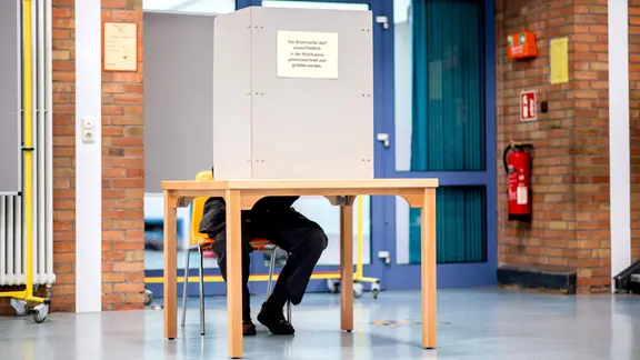 Ein Mann sitzt in einer Wahlkabine bei der Kommunalwahl in Niedersachsen.