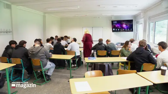 Ein voller Klassenraum mit Schülerinnen, Schülern und einer Lehrerin.