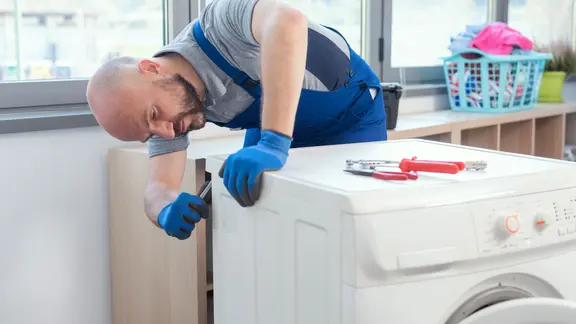 Ein Handwerker repariert eine Waschmaschine. 