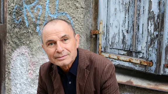 Der Schriftsteller Norbert Gstrein schaut freundlich in die Kamera. 