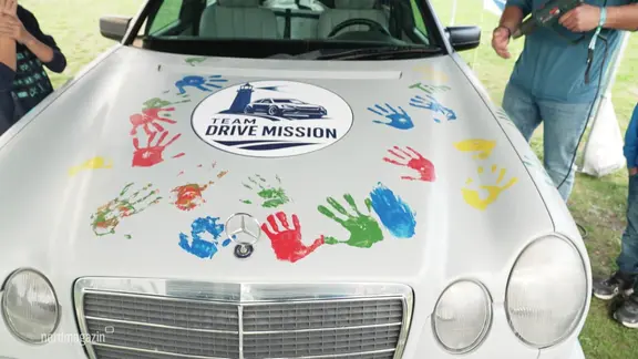 Bunte Kinderhände sind auf ein Auto gemalt.