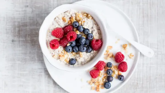 Eine Schüssel mit Quark-Porridge und Beeren steht auf einem Tisch.
