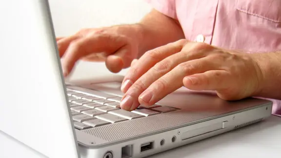 Hände auf der Tastatur eines Laptops.