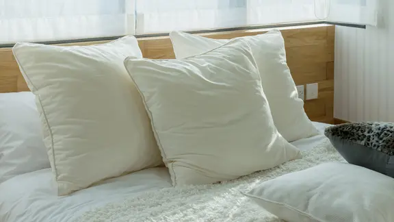 Drei Kissen liegen auf einem Bett.