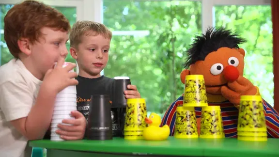 Ernie aus der Sesamstraße und zwei Jungen blicken auf gestapelte Becher 