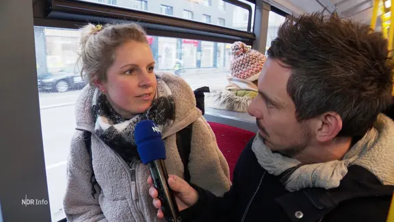 Ein Reporter fragt eine Frau im Bus.