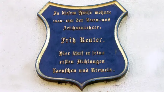 Blaues Wappen zum Gedenken an Fritz Reuter an seinem ehemaligen Wohnhaus in Altentreptow.