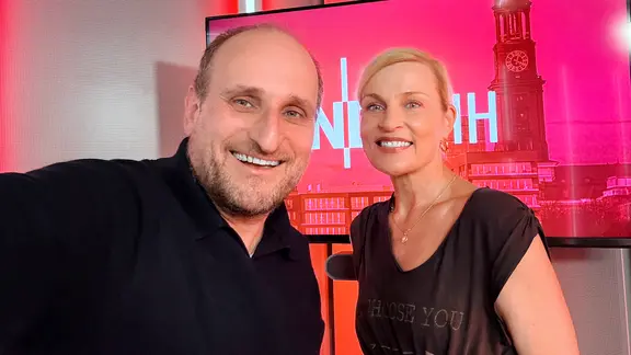 Daniel Kaiser und Sanna Englund stehen vor einem Fernseher.