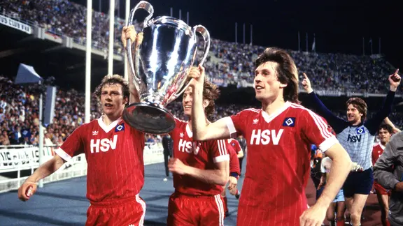 Wolfgang Rolff (l.), Ditmar Jakobs und Manfred Kaltz bejubeln mit dem Pokal den Sieg des HSV im Europacup der Landesmeister 1983.