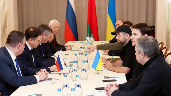Vertreter der russischen und der ukrainischen Regierung sitzen an einem Tisch