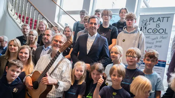 Niedersachsens Minsterpräsident Olaf Lies (SPD) steht zusammen mit Kindern auf einer Treppe.