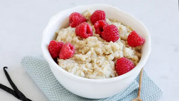 Eine Schale mit einem Porridge, garniert mit Himbeeren.
