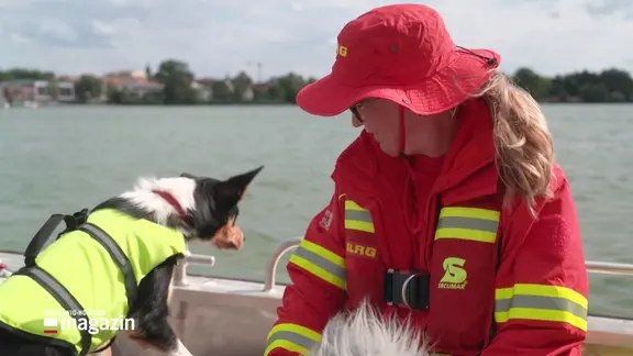 Hund und Frauchen in DLRG-Kleidung auf einem Boot.