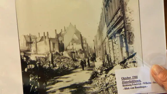 Willi Meyer hält ein historisches Foto der zerstörten Leopoldstraße in der Hand.