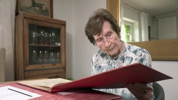 Irmgard Rosenkranz, geborene Gans Edle Herrin zu Putlitz, blättert in einem Fotoalbum.