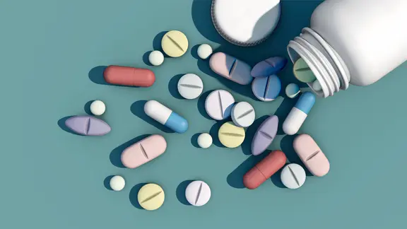 Tabletten fallen aus einem Plastikfläschchen