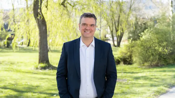 Portrait Landrat Alexander Saipa vor Bäumen und Gebüsch