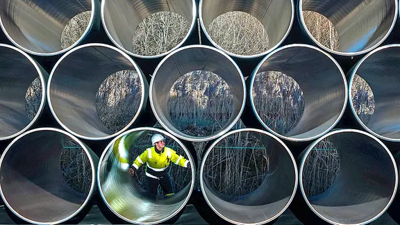 Große Pipeline-Rohre liegen auf Gestellen in einer Fabrikhalle.