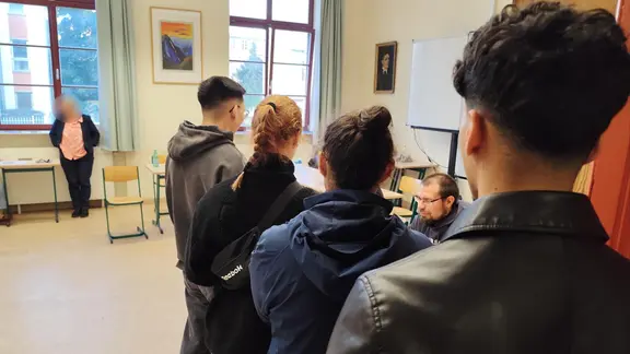 Menschen warten vor der Wahlurne