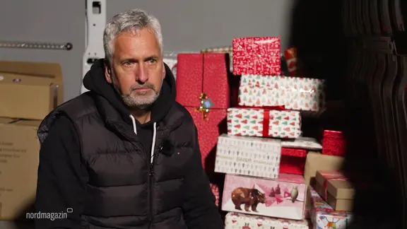Olaf Behm aus Kühlungsborn sitzt in einem Transporter, hinter ihm sind Geschenke gestapelt.