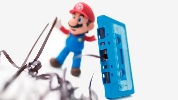 Eine Super Mario Figur steht am 15.11.2017 in Berlin neben einer Kassette mit herausgezogenem Tonband.