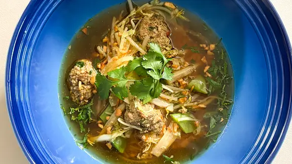 Nudelsuppe mit Hackfleisch und Sojasprossen in einem blauen Suppenteller angerichtet