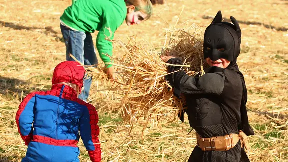 Als Batman und Spiderman verkleidete Kinder werfen mit Stroh.