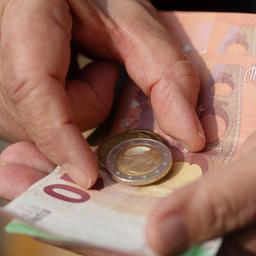 Eine Seniorin hält Euro-Banknoten und Münzen in der Hand.
