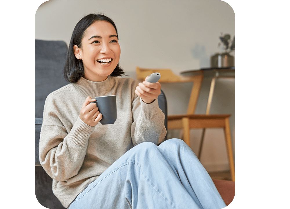 Woman using her Google TV Streamer and remote to access the Google Home panel