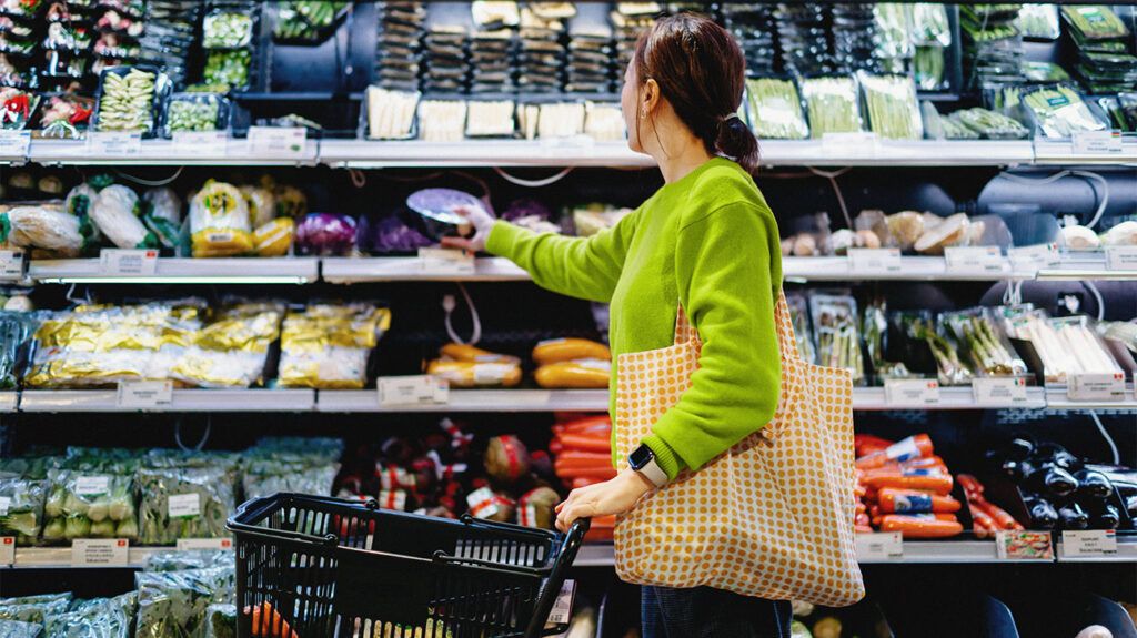 A woman grocery shopping, picking food off a shelf. -2