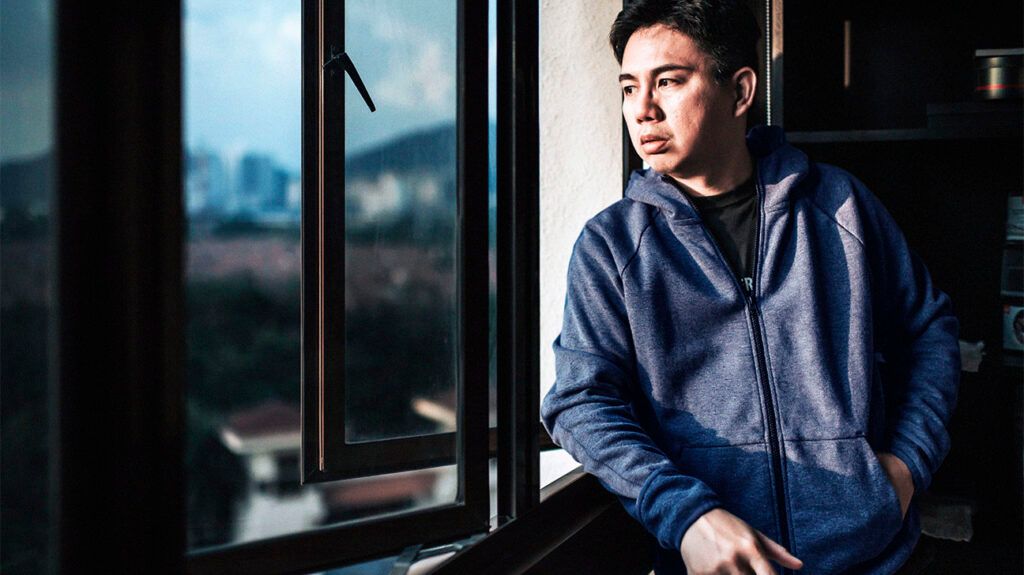 A man experiencing chronic stress staring out a window.-2