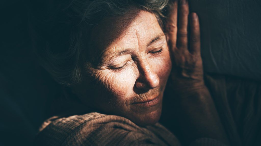 An older woman sleeps as a ray of sun hits her face