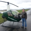 camwyn: Me in a bomber jacket and jeans standing next to a green two-man North Andover Flight Academy helicopter. (helicopter)