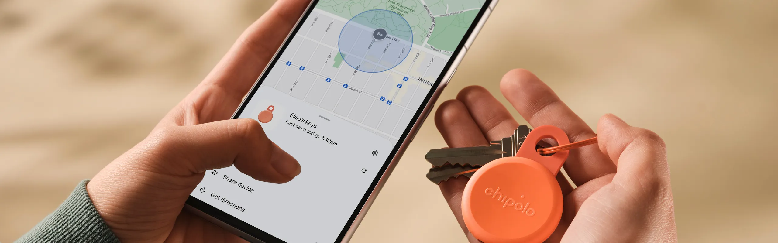 A person holding their phone and in one hand and their keys and tracking tag in another. 