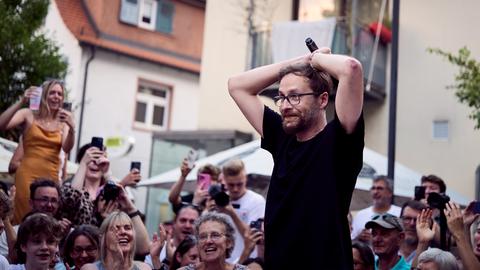 Harry Hegenbarth schlägt die Hände über dem Kopf zusammen. Hinter ihm jubeln Menschen.