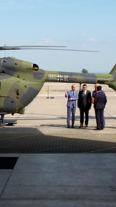 Vier Männer stehen vor einem Hubschrauber auf einem Flugfeld.