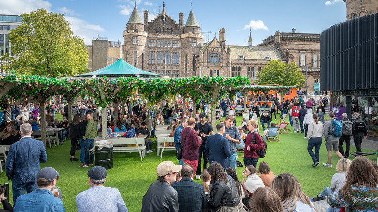 Festival-goers on a lawn with historic buildings in the background in Edinburgh