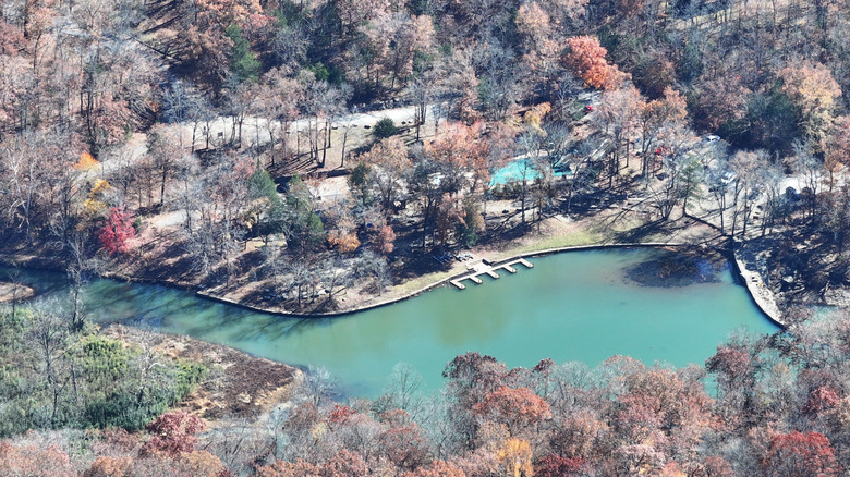 An aerial view of a blue lake surrounded by orange and brown-leafed trees in Devil's Den State Park, Arkansas