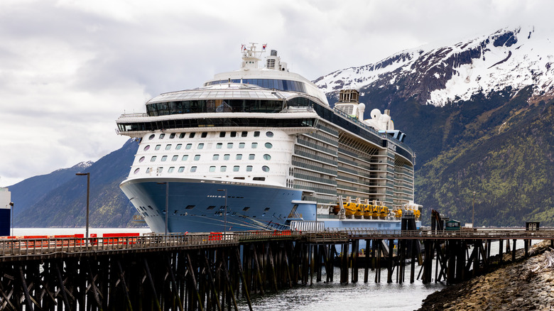 A cruise ship docked with the Alaskan mountains in the background