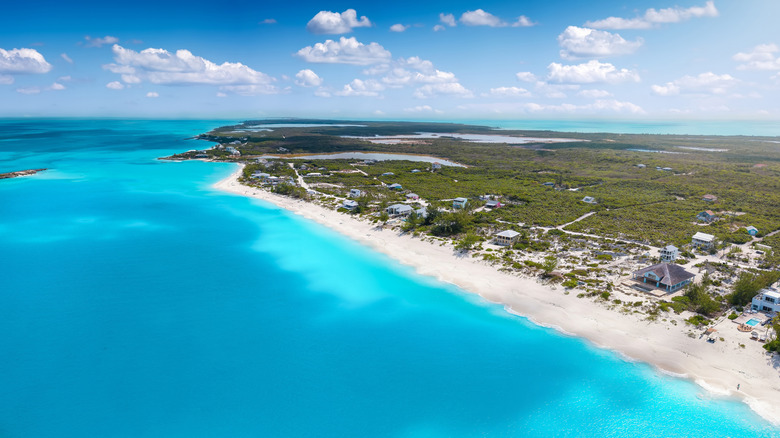 An aerial view of a beach with bright blue water and white sand