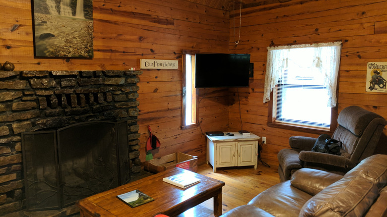 a small, cozy living room with a stone fireplace in the Buffalo Outdoor Center