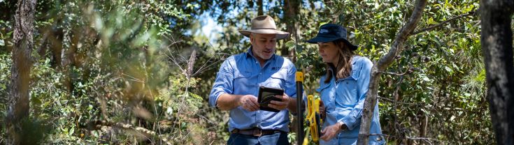 2 biodiversity conservation officers in the bush taking measurements