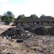 Large mounds of earth and debris can be seen on cleared land near the Norman Lodge site.