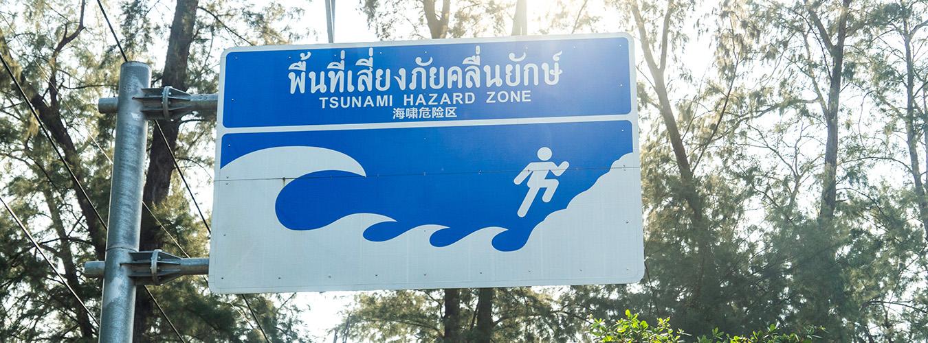 Warning sign indicating a tsunami hazard zone near a coastal area.