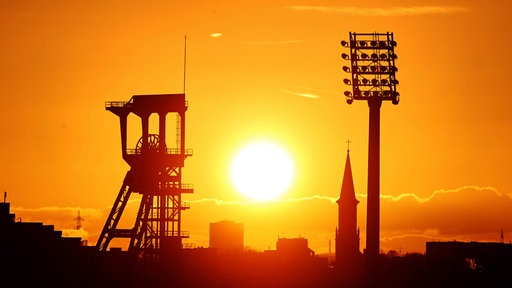 Die Sonne geht über dem Förderturm der Zeche Holland auf.