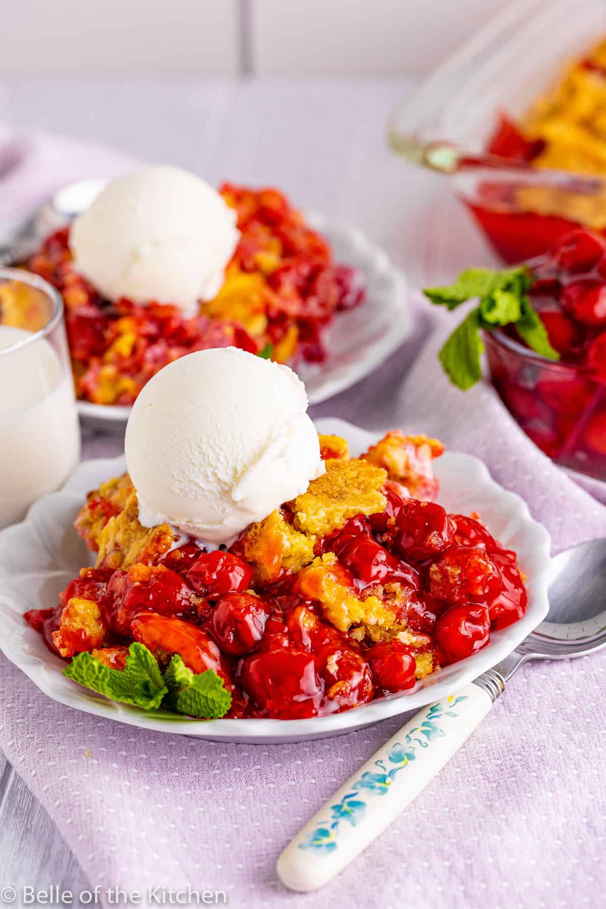 two plates of cherry dump cake with ice cream on top.