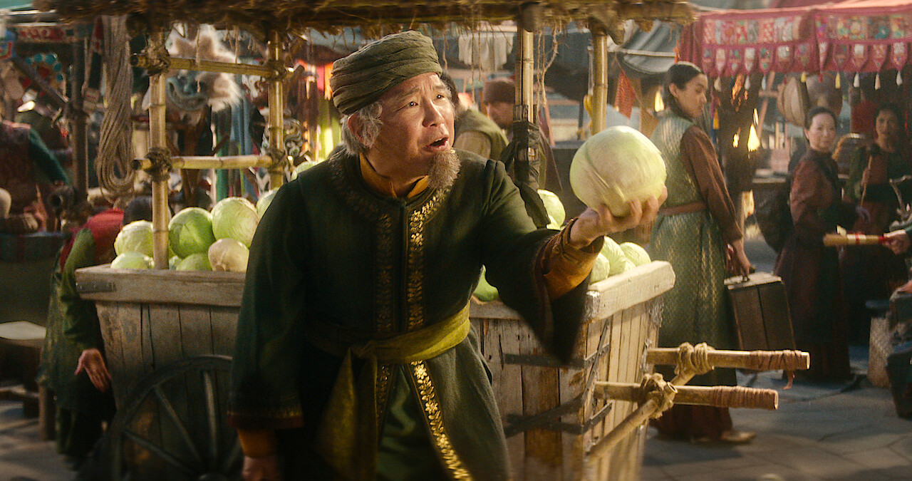 ames Sie as Cabbage Merchant holds a cabbage at a market in season 1 of 'Avatar: The Last Airbender'