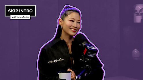 Arden Cho behind a microphone, set against a purple background.
